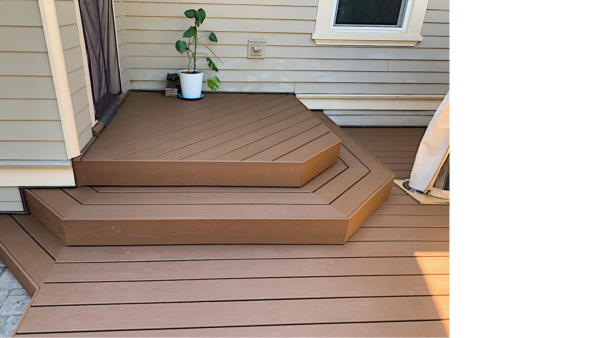 Angled composite entry steps leading from a back door to a custom brown deck